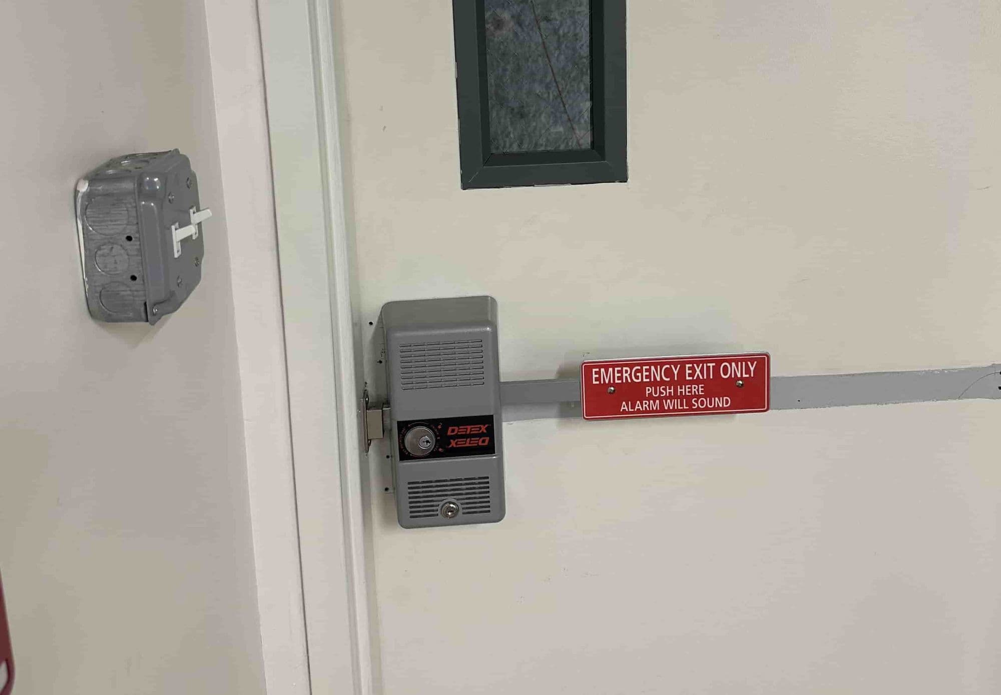 Commercial door with an emergency exit bar and alarm